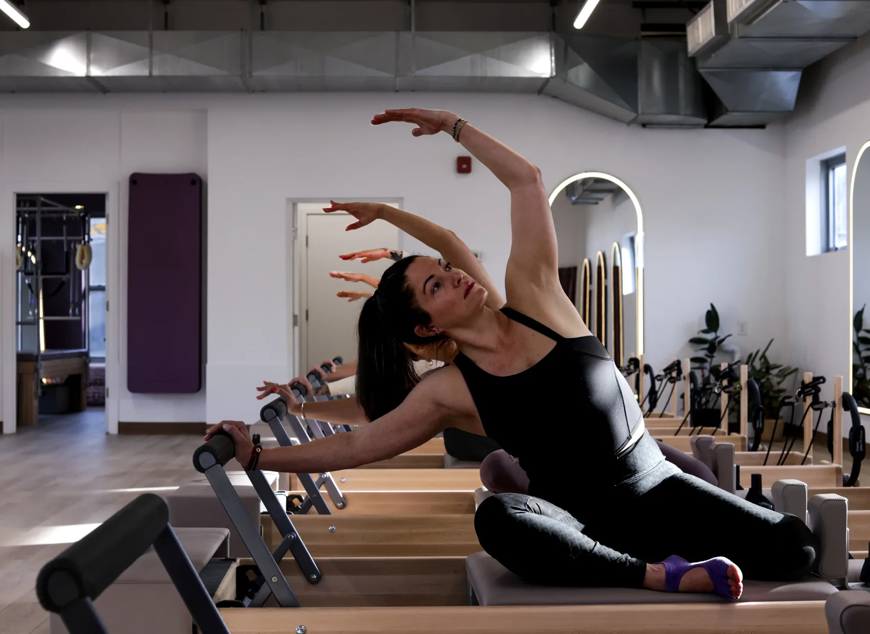 A member moving through a side-stretch on the reformer at Stellar Pilates in Pittsburgh